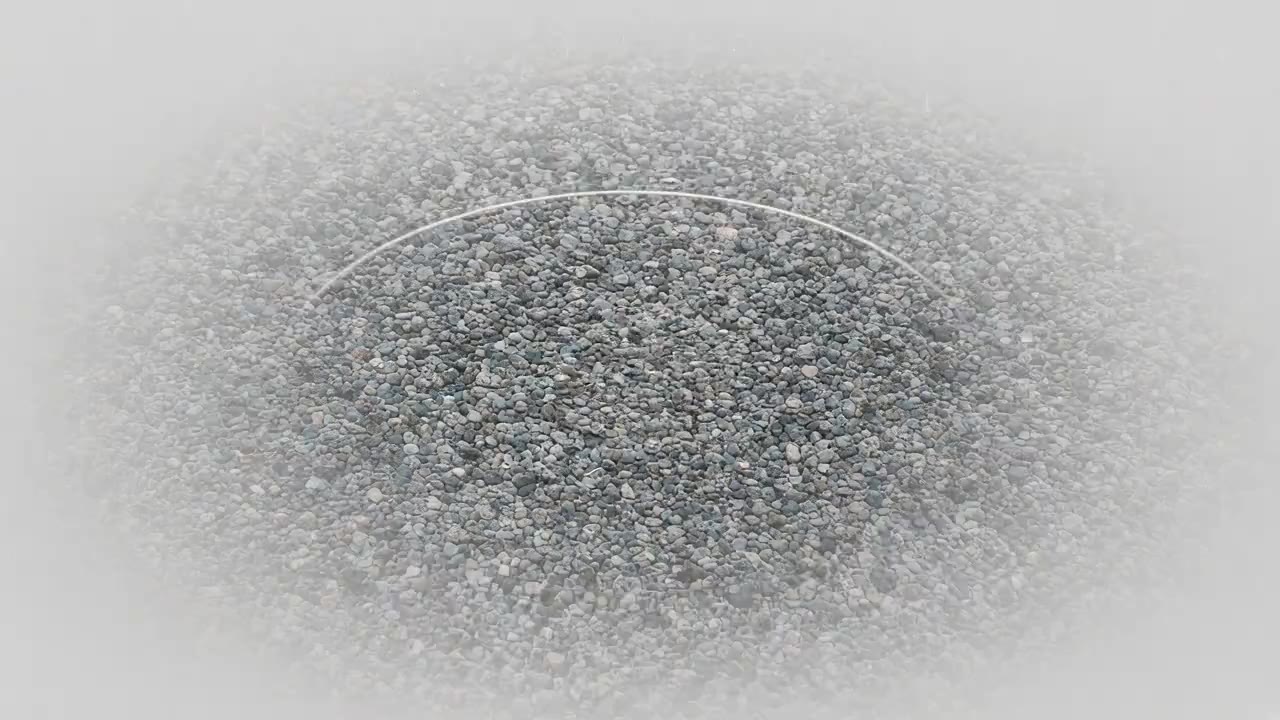 A generated picture of rain rings spreading on a shallow puddle over grey drive gravel.