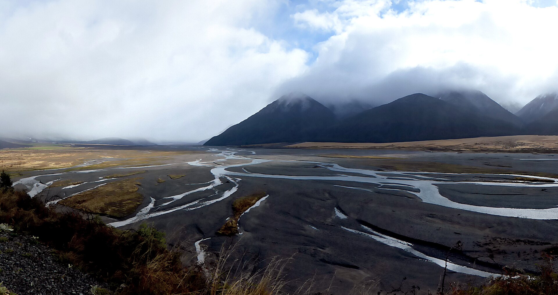 A moody braided Canterbury river spreading across wide gravel flats under low cloud.